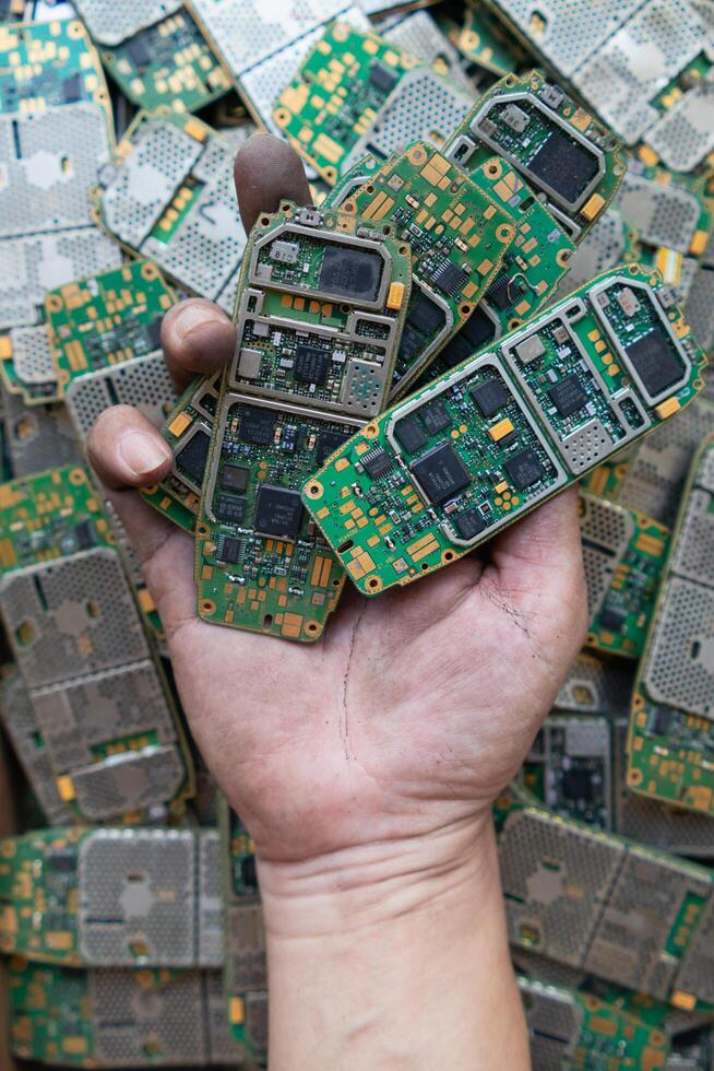 pile of electronic waste on factory floor is circuit board of mobile phone waiting to be processed extract gold to separate precious metal from electronic waste. extracting precious metal from e-waste photo