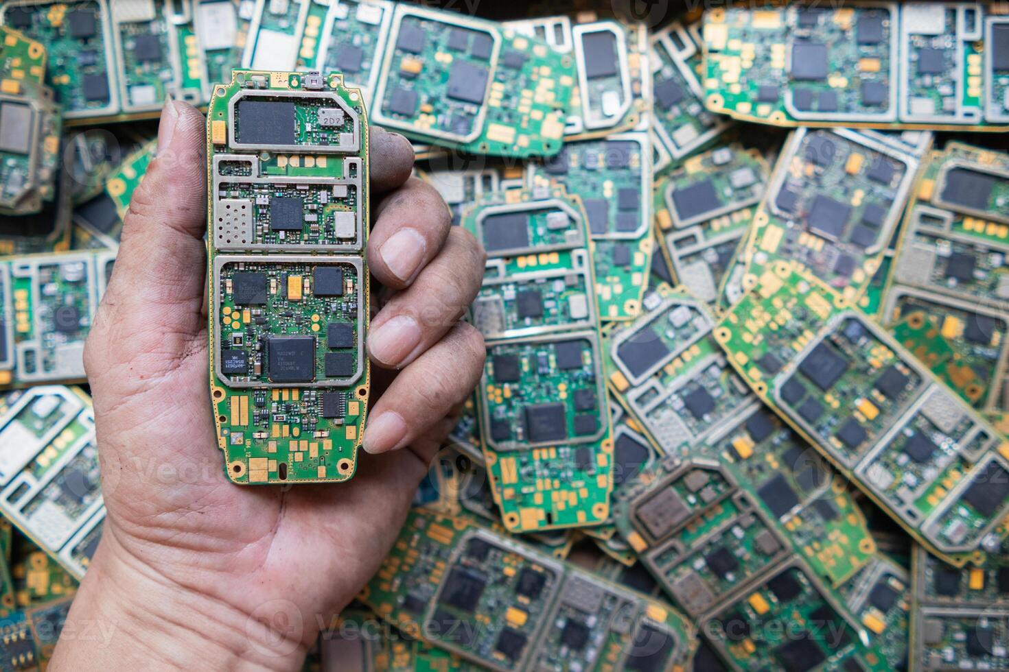 pile of electronic waste on factory floor is circuit board of mobile phone waiting to be processed extract gold to separate precious metal from electronic waste. extracting precious metal from e-waste photo
