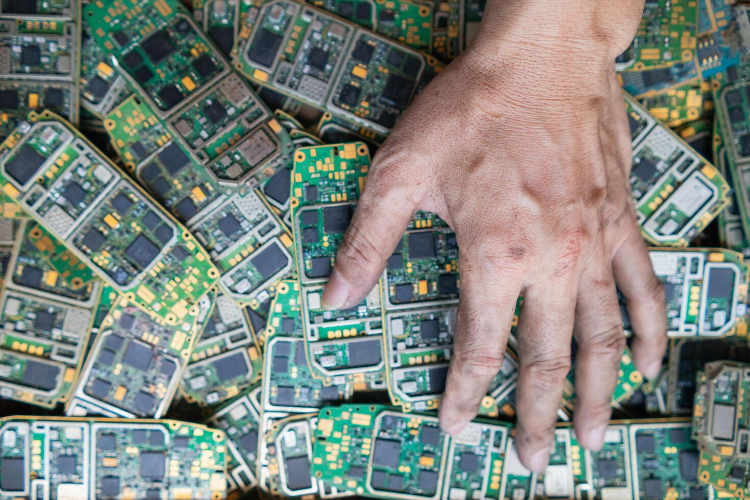 pile of electronic waste on factory floor is circuit board of mobile phone waiting to be processed extract gold to separate precious metal from electronic waste. extracting precious metal from e-waste photo