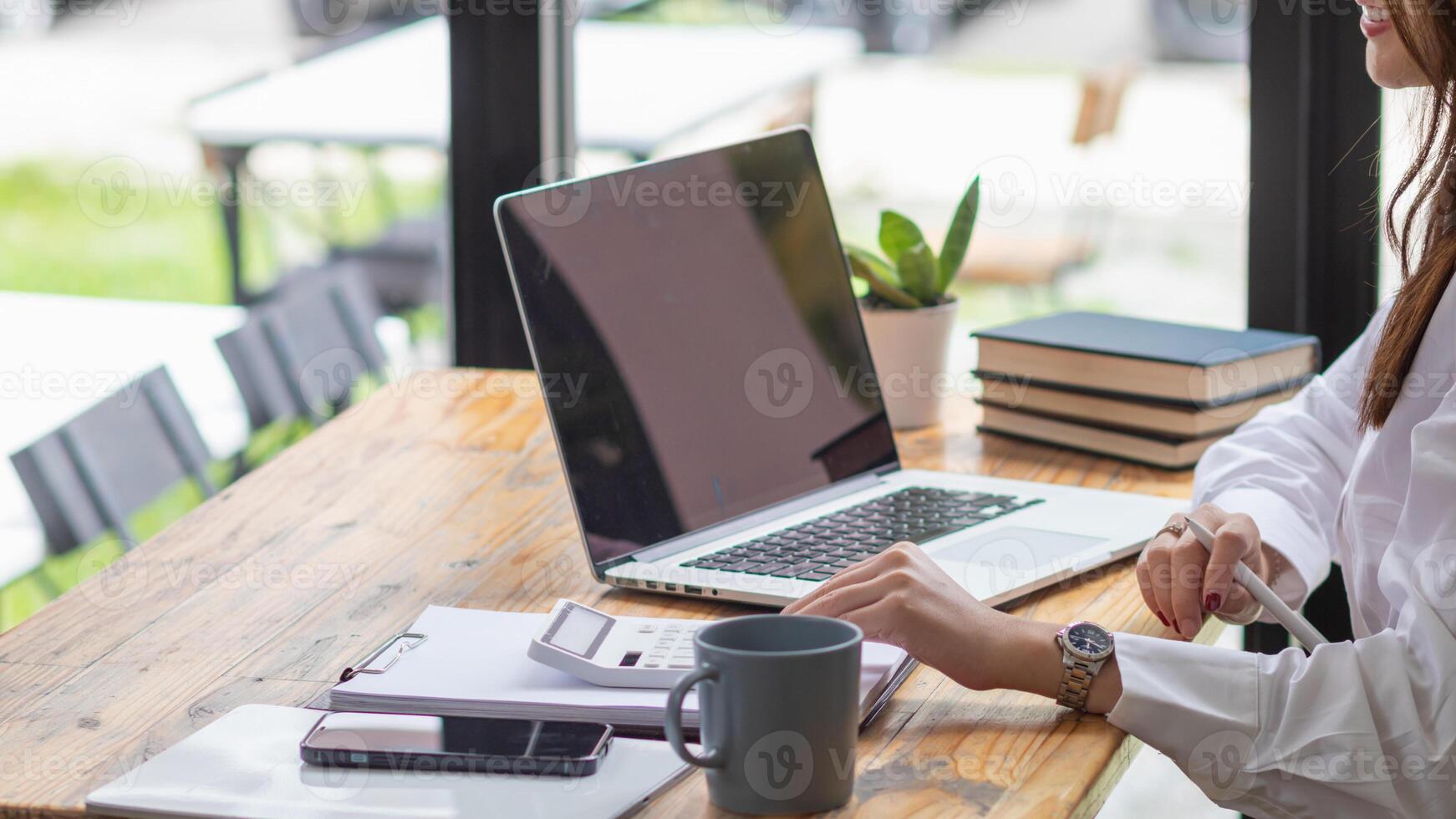 young businesswoman is reviewing results of corporate network via laptops and the Internet in order to prepare documents for meetings to give investors confidence in doing business. photo