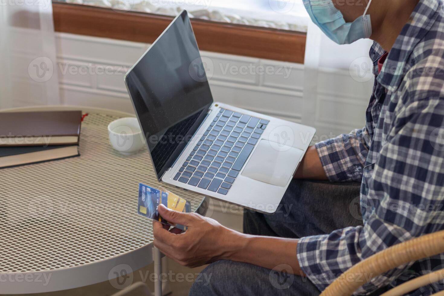 A young man is using a credit card to pay for online shopping during breaks to get the products he wants from online stores without having to travel by himself and at the convenience of you photo