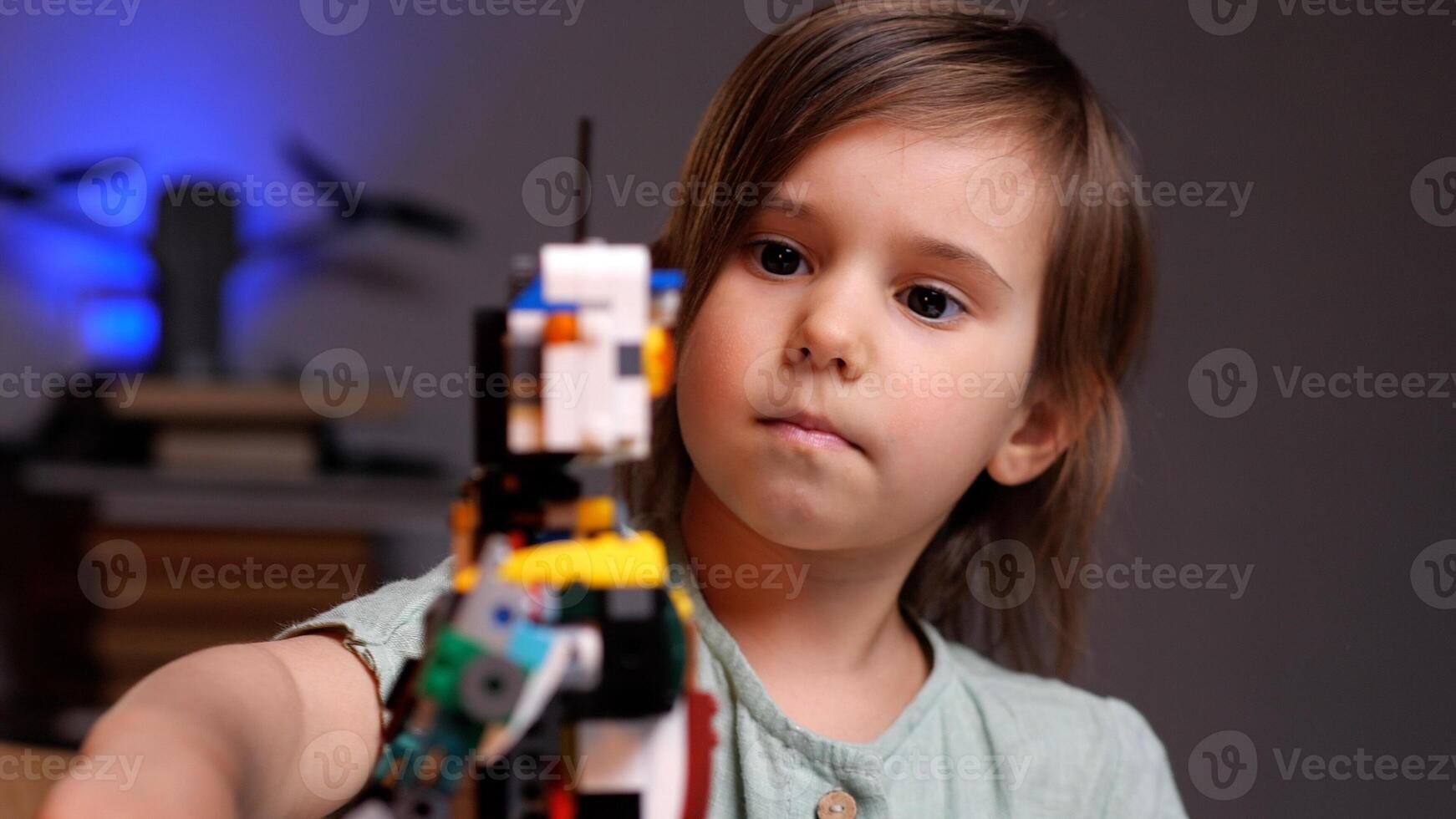 Little girl playing with robot from plastic bricks photo