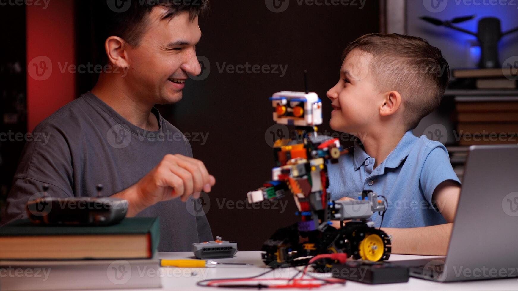 Father and son building robot and programming it at home photo
