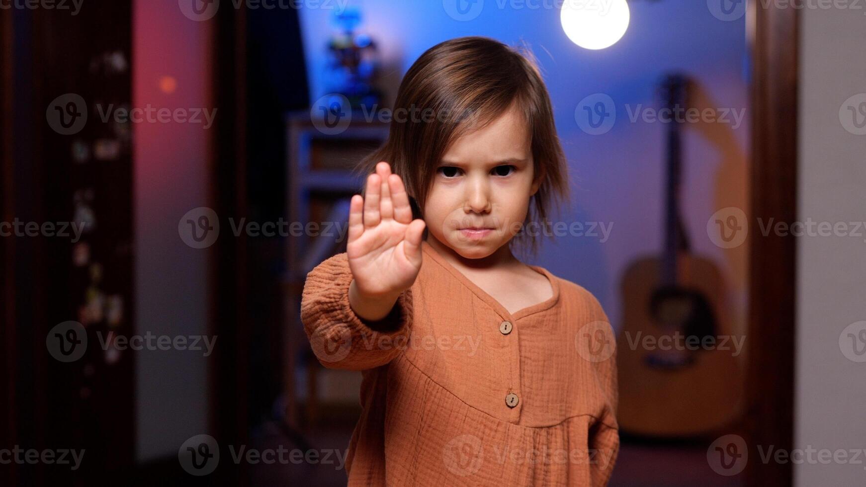 Serious little girl showing stop gesture with hand at home photo