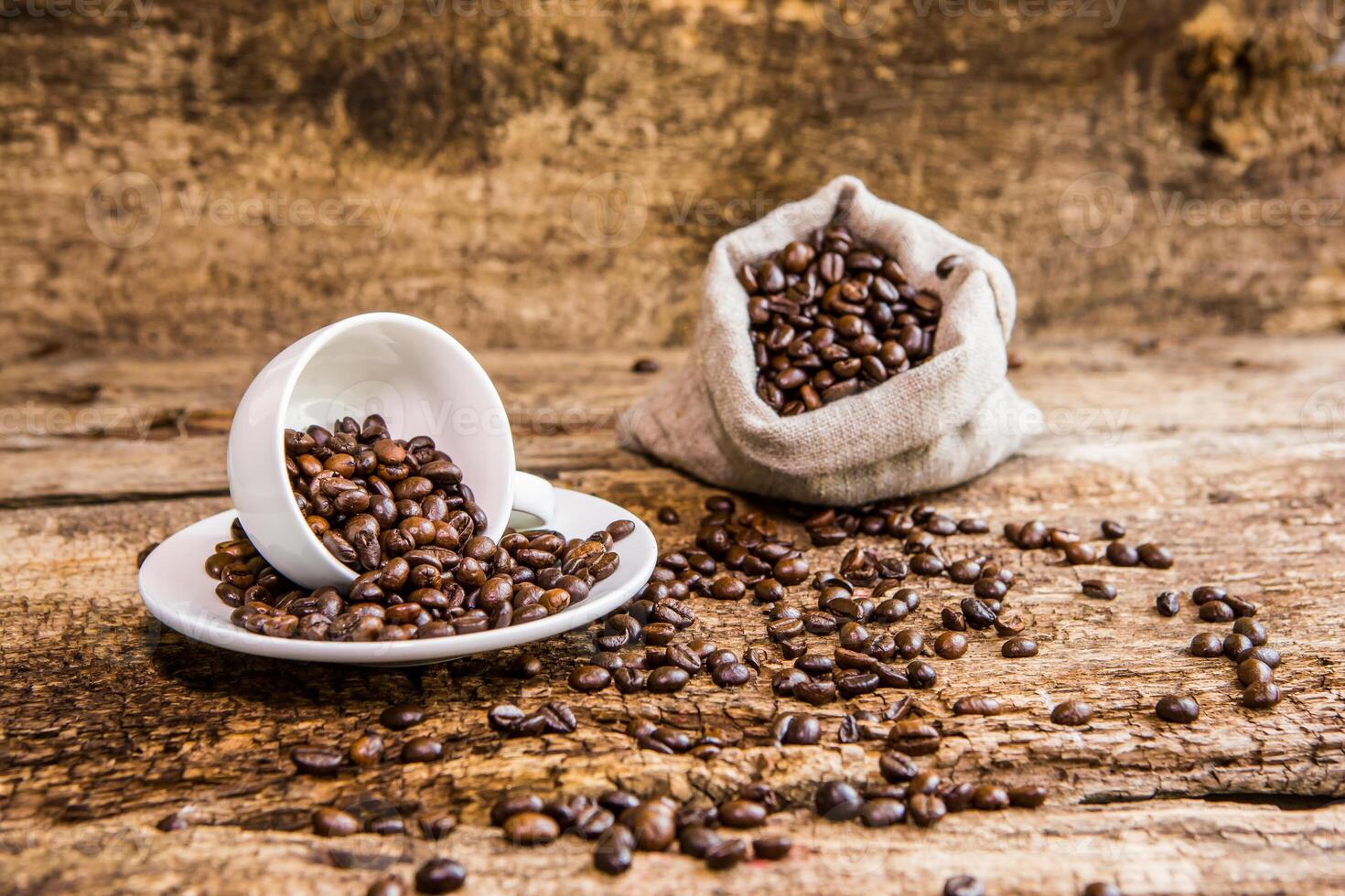 Coffee beans in a white mug. Coffee beans on a wooden background. A bag of coffee beans. Dark background. photo