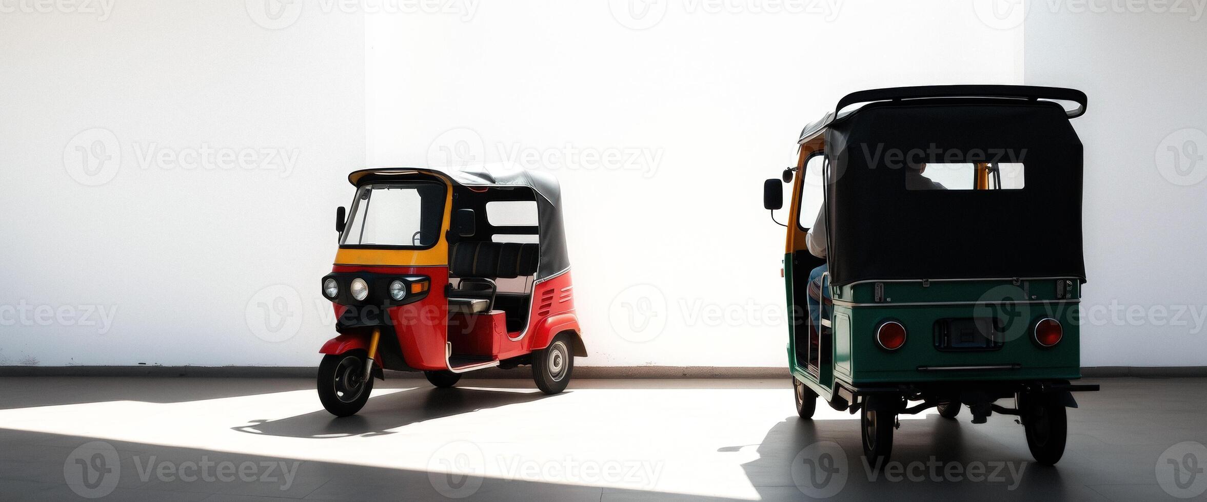 Two auto rickshaws parked in front of a white wall photo
