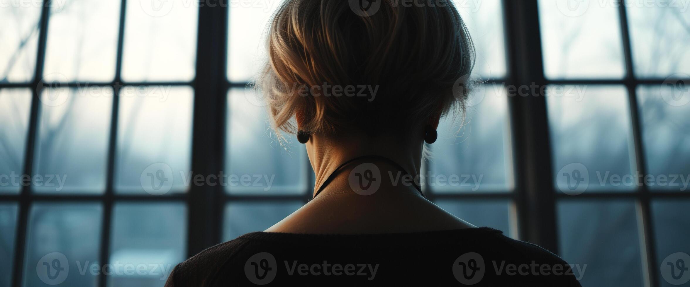 Woman in black top, looking out window photo