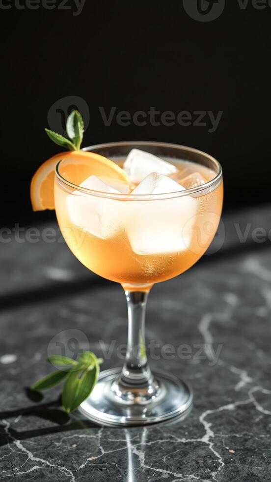 Orange Cocktail with Ice Cubes in a Glass on a Marble Surface photo