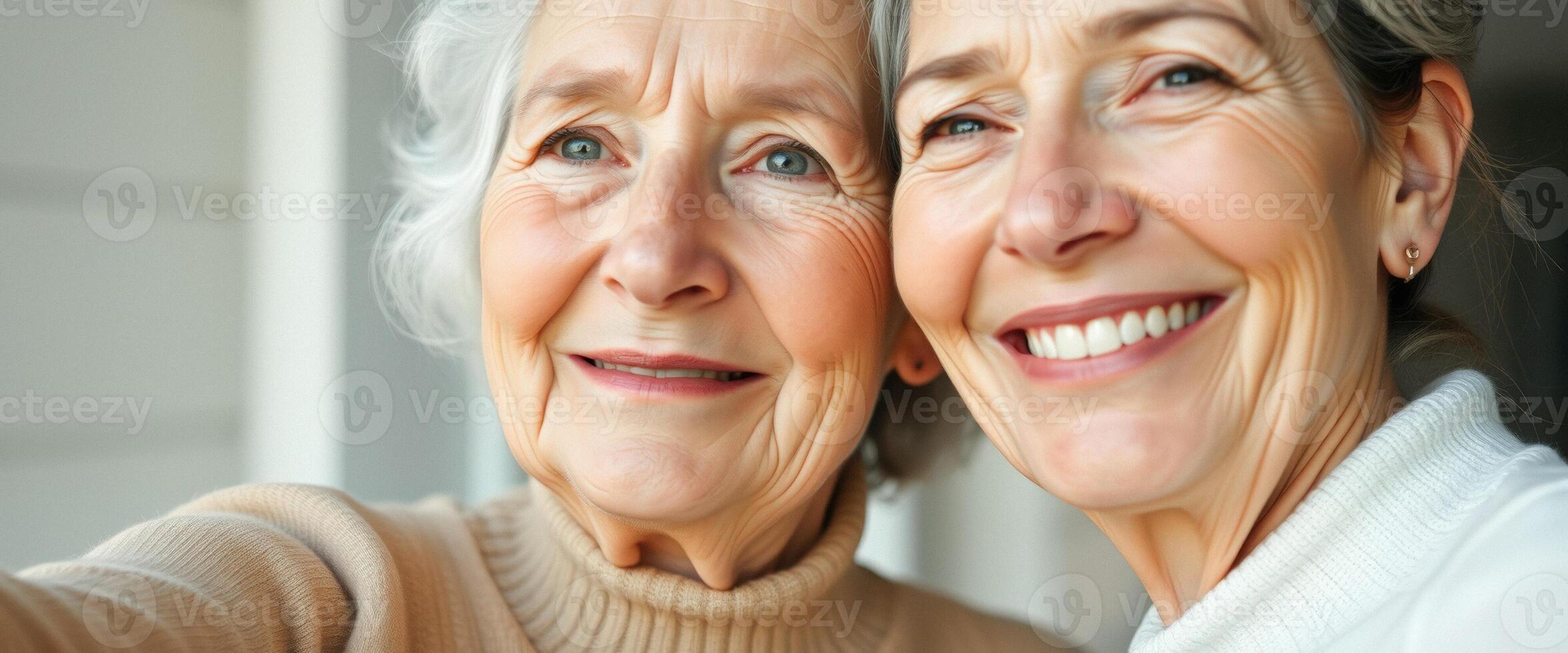 Close-up of two smiling women, one with grey hair and the other with brown hair photo