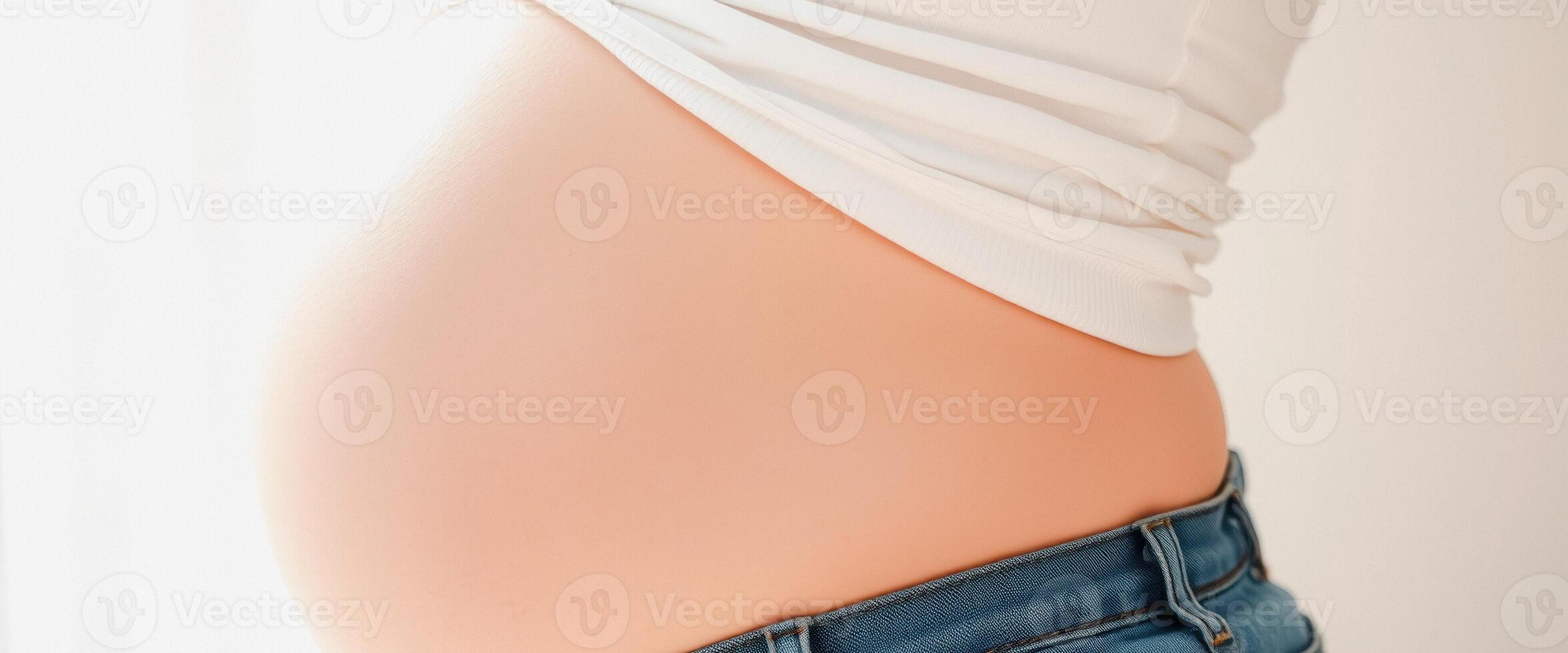 Pregnant Woman's Belly with White Shirt and Jeans photo