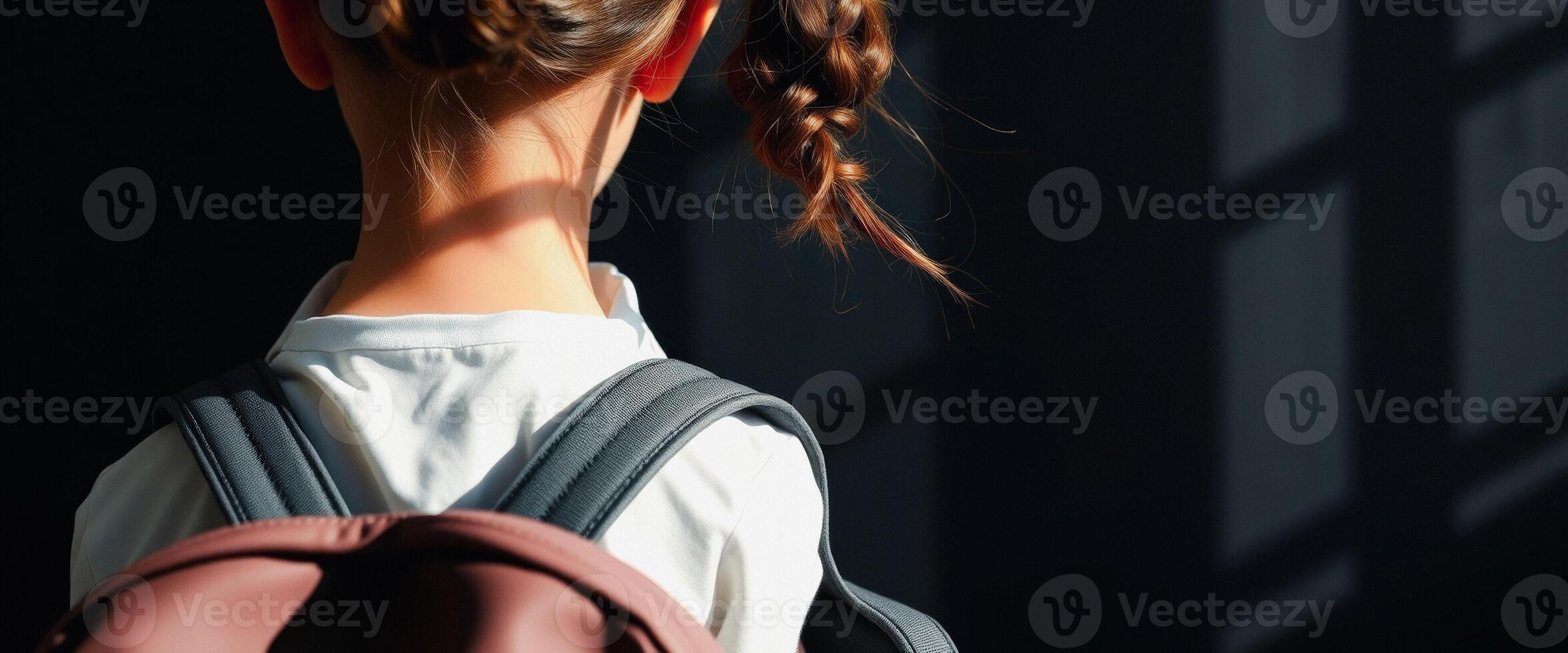 Little girl with backpack standing in the light photo