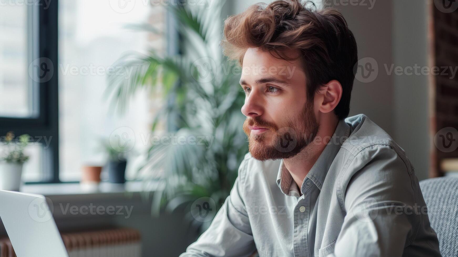 Thoughtful Young Man Looking Away from Laptop photo