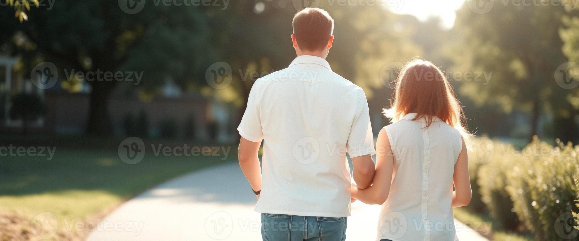 Back view of a young couple walking in the park on a sunny day photo