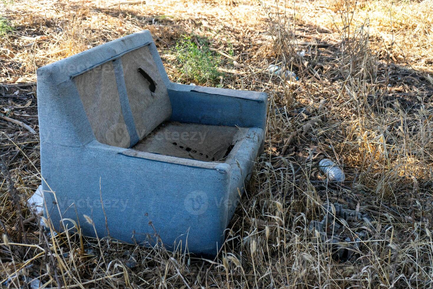 Plastic bottles and an old sofa discarded in a field, showcasing the disturbing impact of human waste on nature. photo