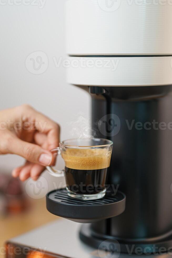 hand making Espresso Coffee by Coffee Maker Machine with Capsule of roasted coffee bean on wood table bar. Daily beverage drink at Home, Apartment and Office concept photo