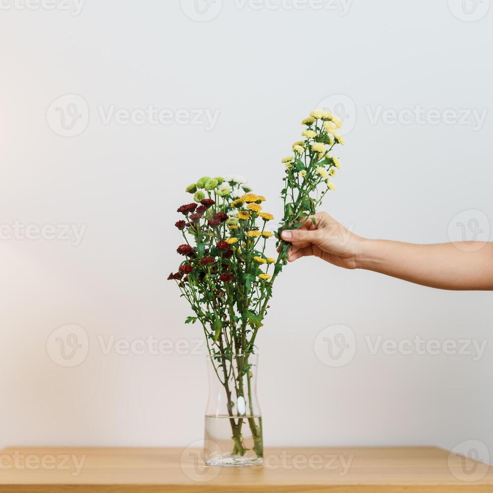 Woman hand arrange Colorful flowers bouquet in mason jar on table background. Happy day with fresh flower photo