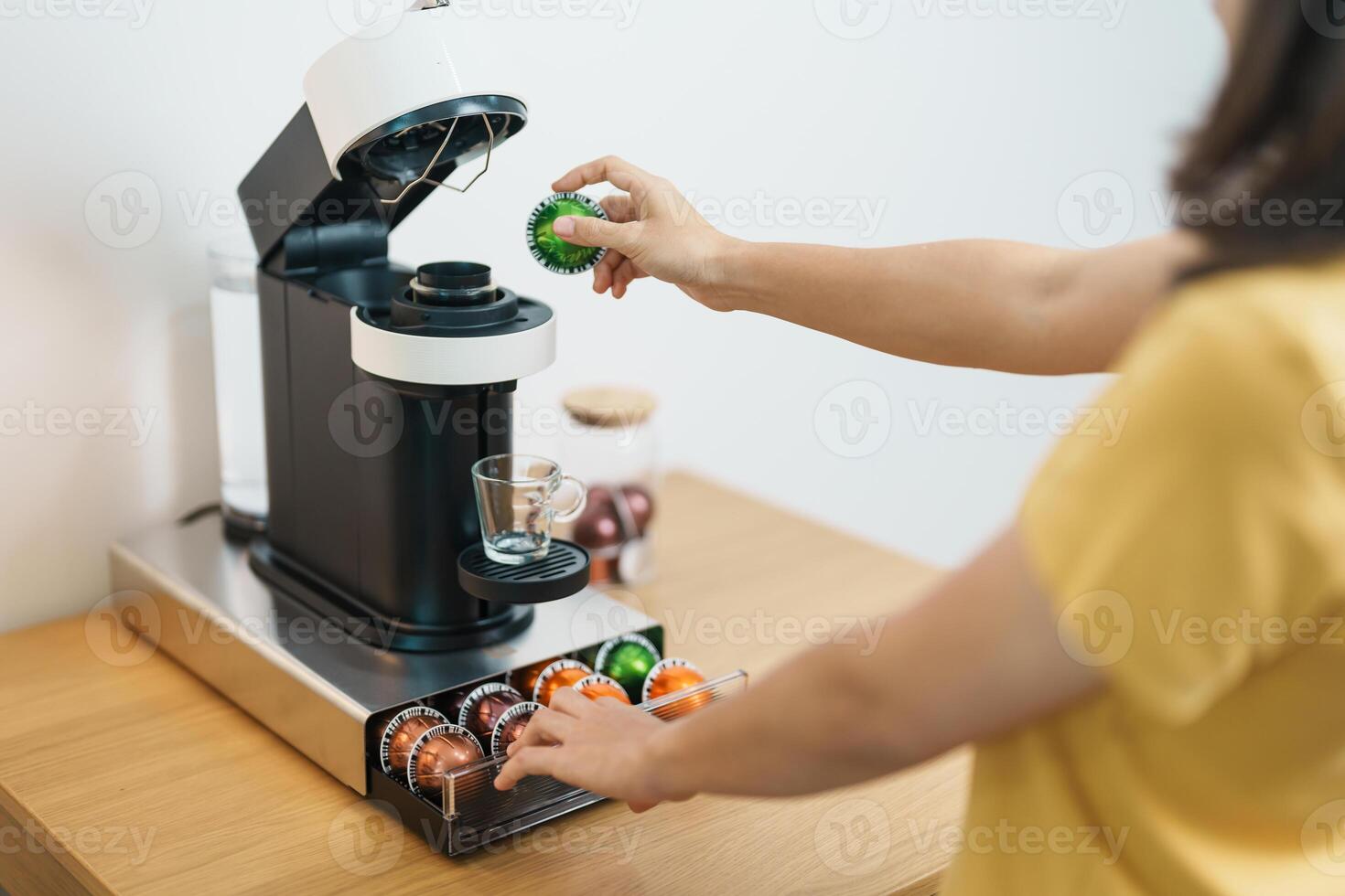 hand making Espresso Coffee by Coffee Maker Machine with Capsule of roasted coffee bean on wood table bar. Daily beverage drink at Home, Apartment and Office concept photo