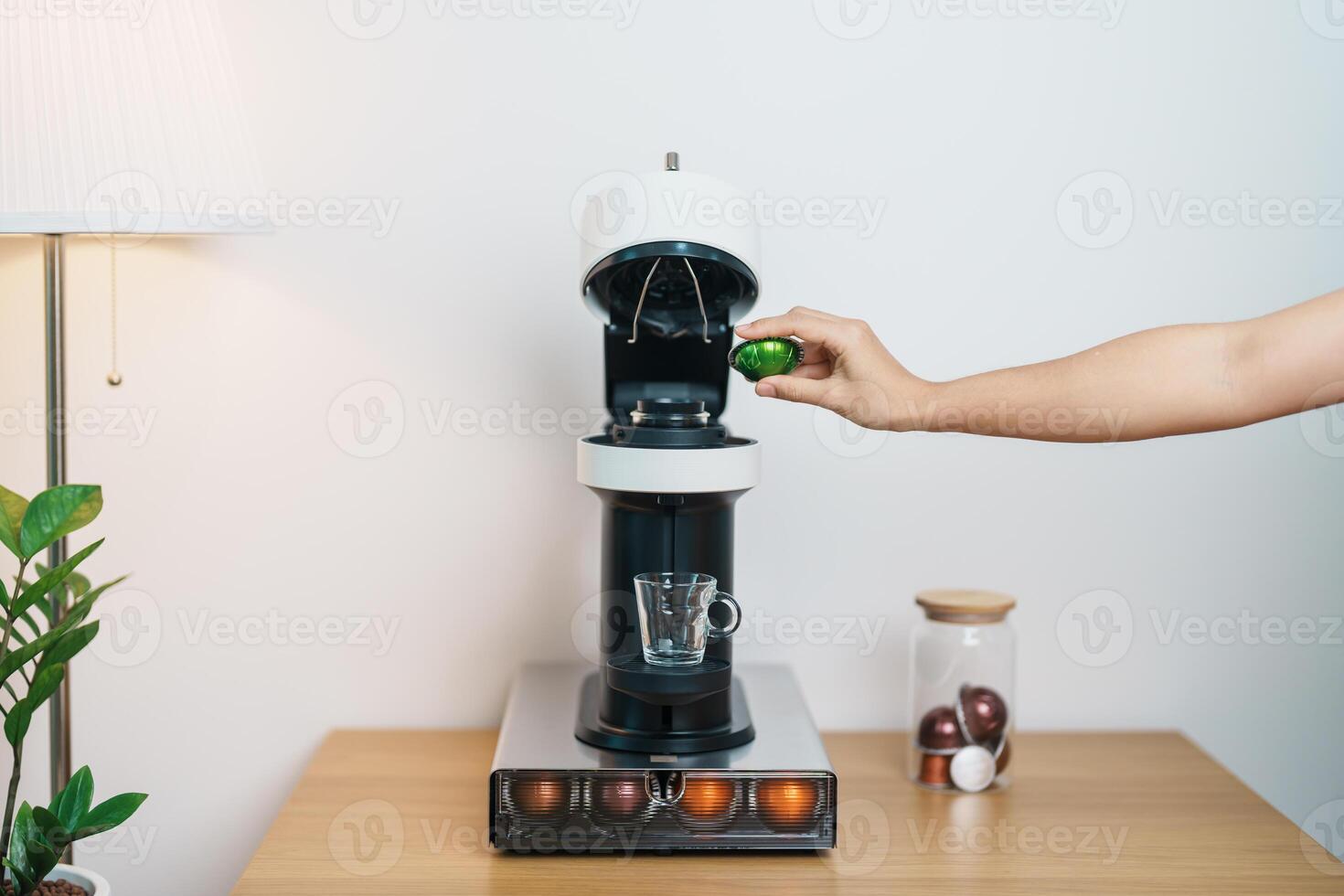 hand making Espresso Coffee by Coffee Maker Machine with Capsule of roasted coffee bean on wood table bar. Daily beverage drink at Home, Apartment and Office concept photo