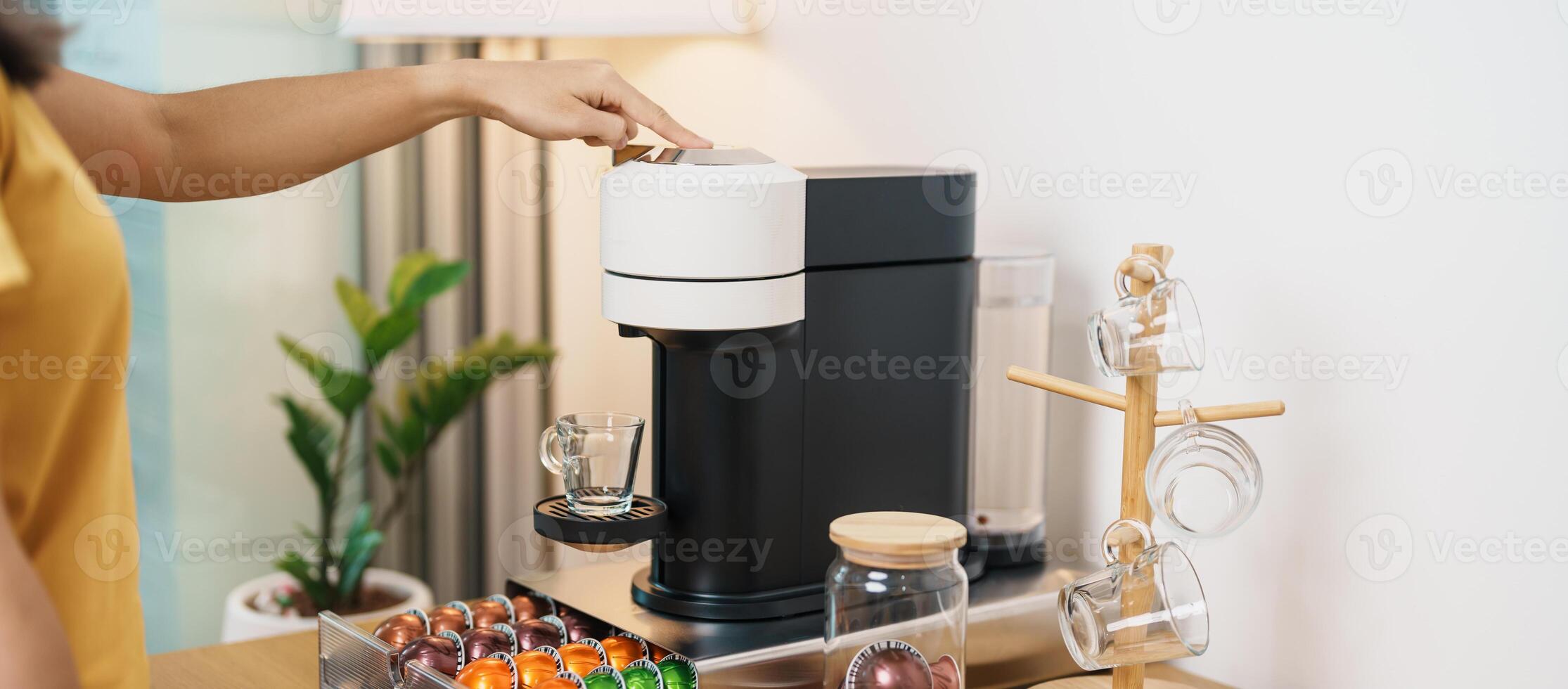 hand making Espresso Coffee by Coffee Maker Machine with Capsule of roasted coffee bean on wood table bar. Daily beverage drink at Home, Apartment and Office concept photo