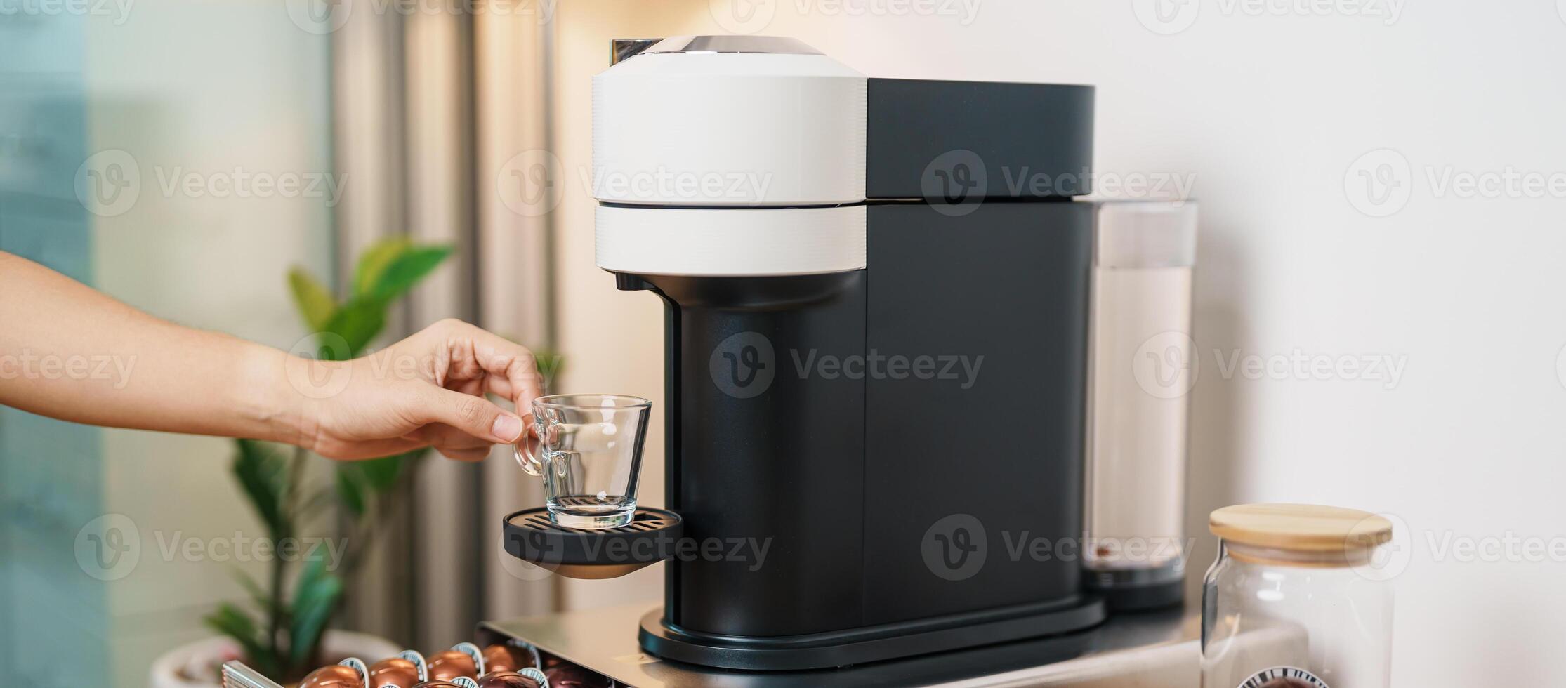 hand making Espresso Coffee by Coffee Maker Machine with Capsule of roasted coffee bean on wood table bar. Daily beverage drink at Home, Apartment and Office concept photo