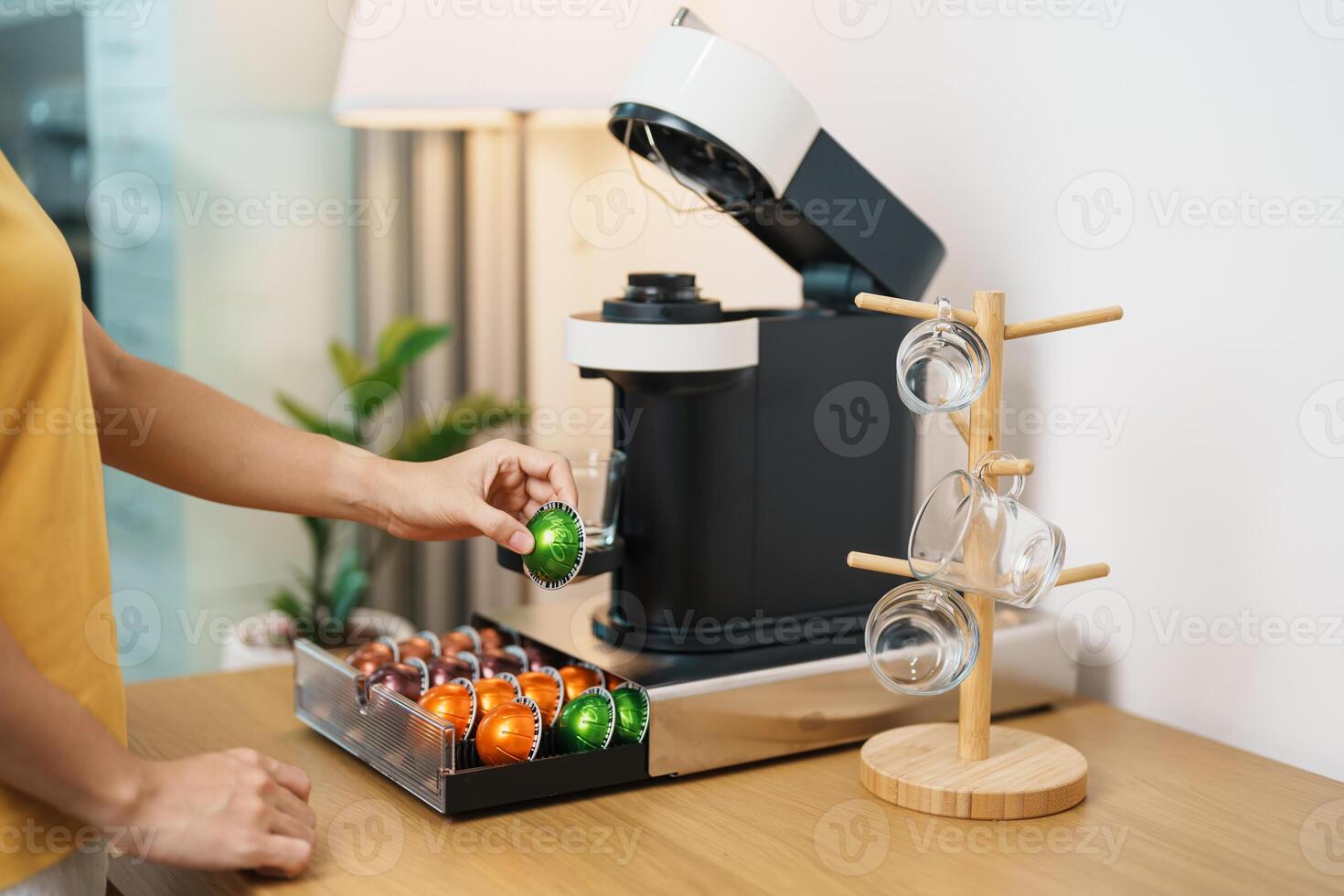 hand making Espresso Coffee by Coffee Maker Machine with Capsule of roasted coffee bean on wood table bar. Daily beverage drink at Home, Apartment and Office concept photo