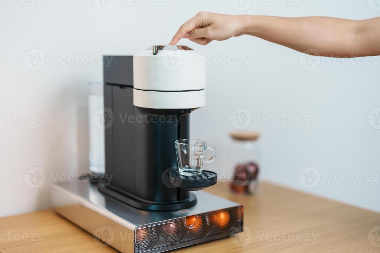 hand making Espresso Coffee by Coffee Maker Machine with Capsule of roasted coffee bean on wood table bar. Daily beverage drink at Home, Apartment and Office concept photo