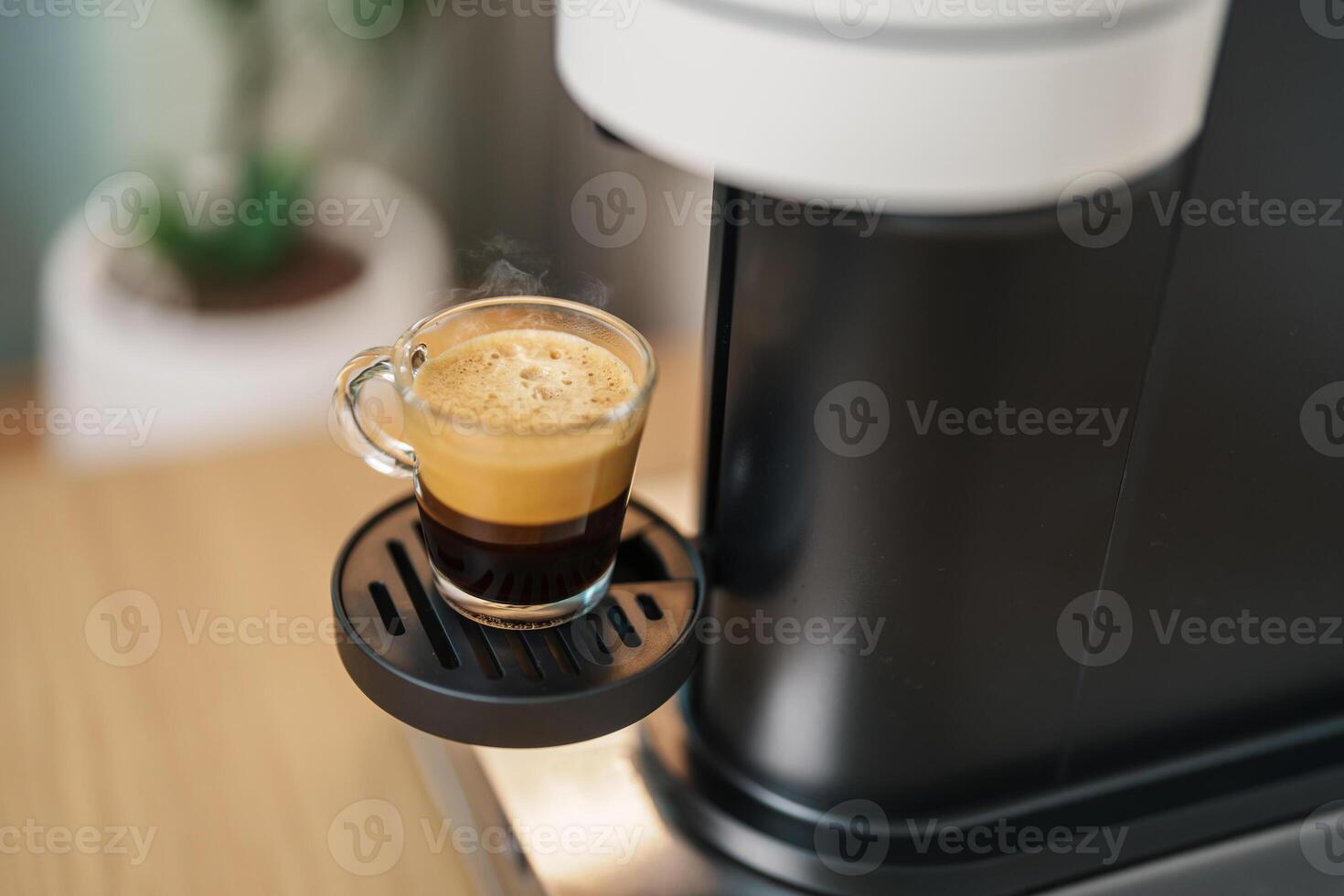Espresso cup with steam and froth during Coffee making Coffee by Coffee Maker Machine on wood table bar. Cafe shop, Daily beverage drink at Home, Apartment and Office concept photo