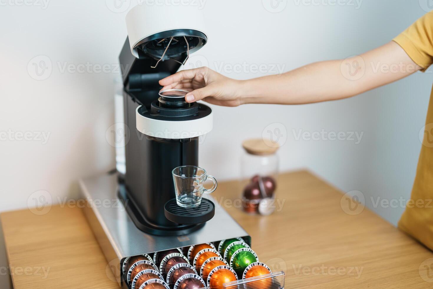 hand making Espresso Coffee by Coffee Maker Machine with Capsule of roasted coffee bean on wood table bar. Daily beverage drink at Home, Apartment and Office concept photo