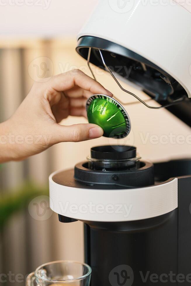 hand making Espresso Coffee by Coffee Maker Machine with Capsule of roasted coffee bean on wood table bar. Daily beverage drink at Home, Apartment and Office concept photo