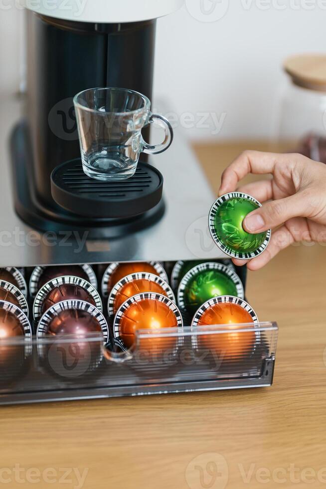 hand making Espresso Coffee by Coffee Maker Machine with Capsule of roasted coffee bean on wood table bar. Daily beverage drink at Home, Apartment and Office concept photo