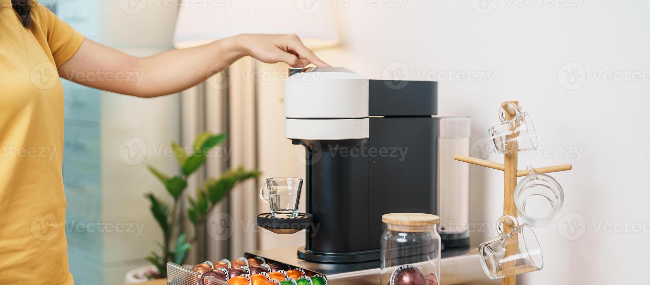 hand making Espresso Coffee by Coffee Maker Machine with Capsule of roasted coffee bean on wood table bar. Daily beverage drink at Home, Apartment and Office concept photo