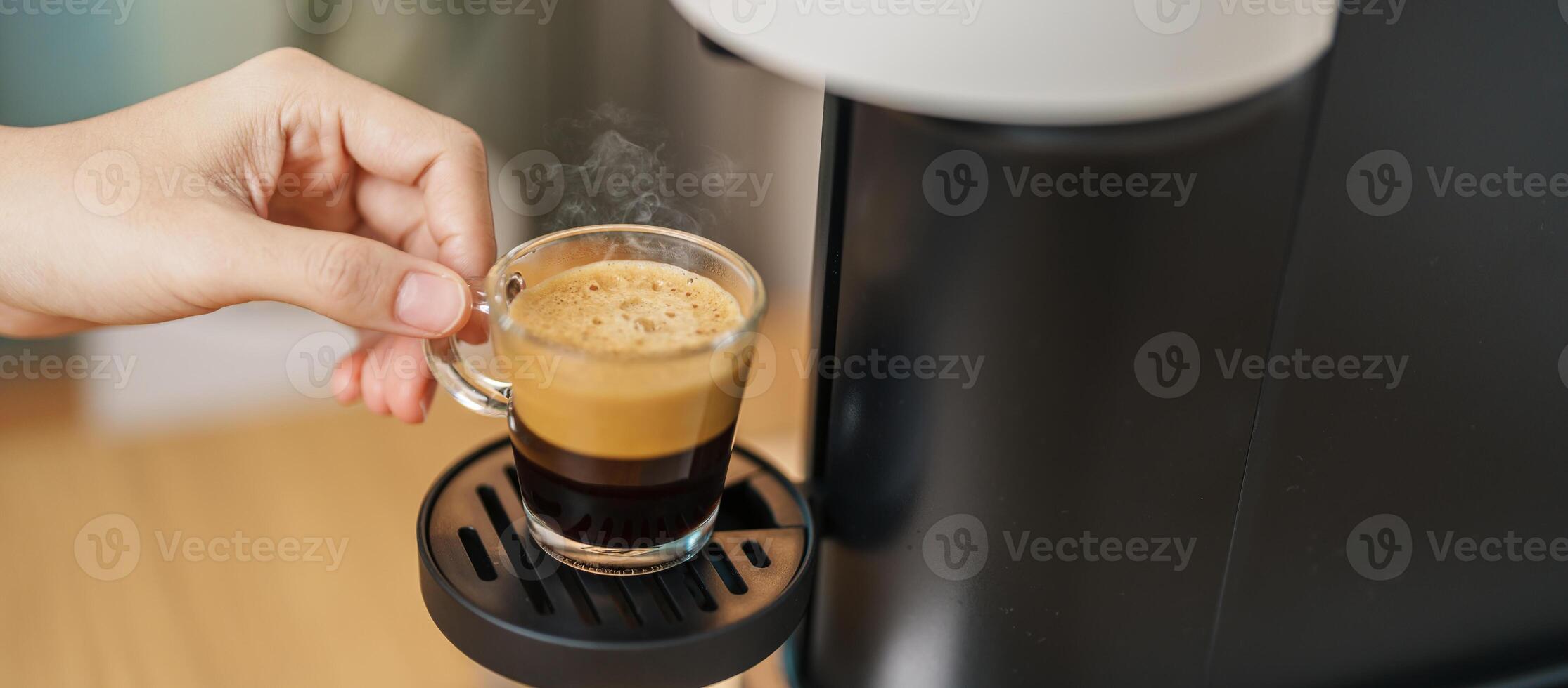 Espresso cup with steam and froth during Coffee making Coffee by Coffee Maker Machine on wood table bar. Cafe shop, Daily beverage drink at Home, Apartment and Office concept photo