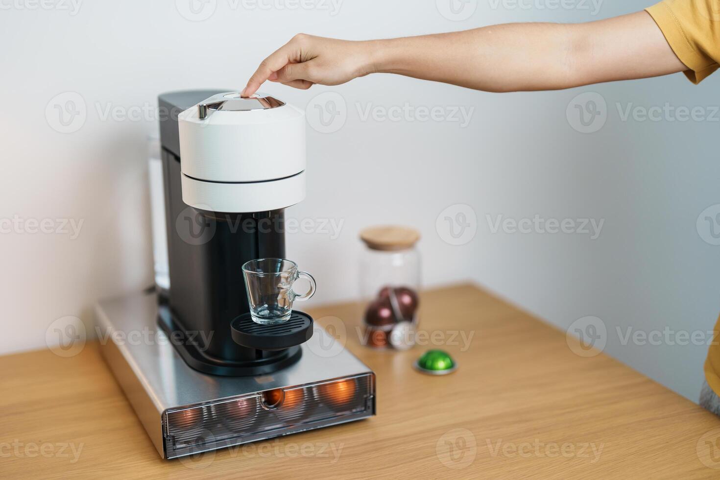 hand making Espresso Coffee by Coffee Maker Machine with Capsule of roasted coffee bean on wood table bar. Daily beverage drink at Home, Apartment and Office concept photo