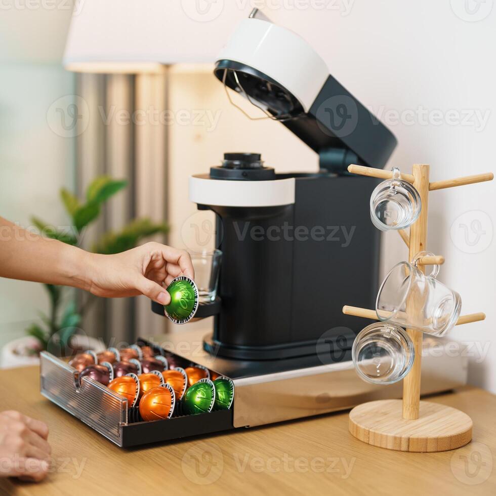 hand making Espresso Coffee by Coffee Maker Machine with Capsule of roasted coffee bean on wood table bar. Daily beverage drink at Home, Apartment and Office concept photo