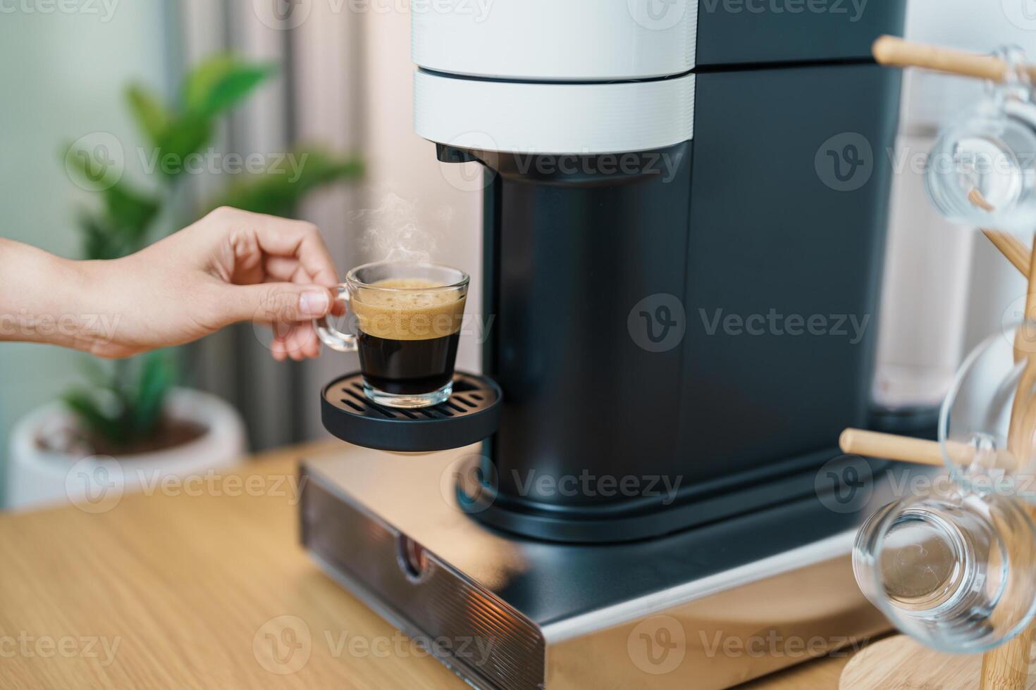 hand making Espresso Coffee by Coffee Maker Machine with Capsule of roasted coffee bean on wood table bar. Daily beverage drink at Home, Apartment and Office concept photo