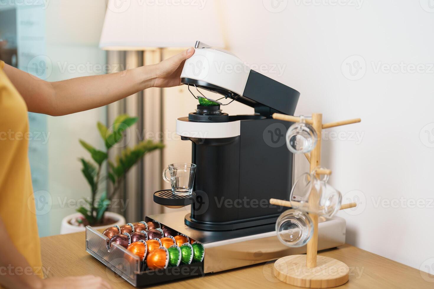 hand making Espresso Coffee by Coffee Maker Machine with Capsule of roasted coffee bean on wood table bar. Daily beverage drink at Home, Apartment and Office concept photo