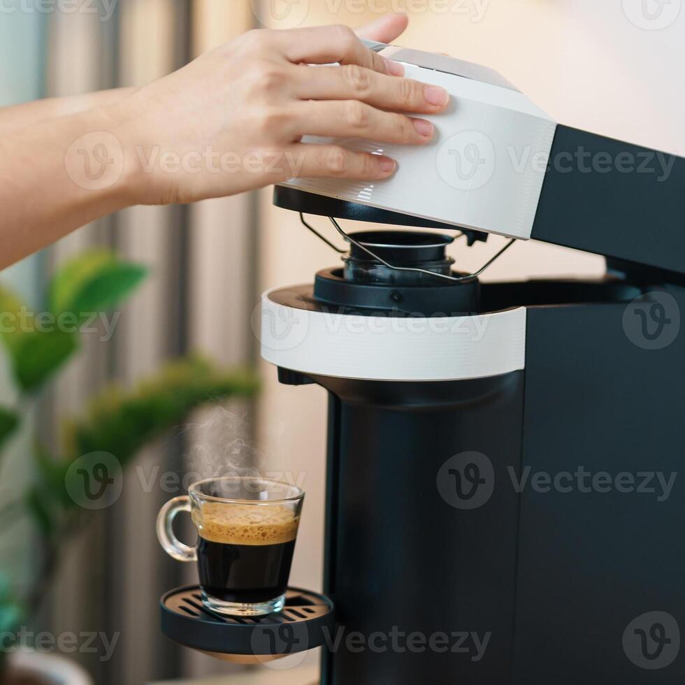 hand making Espresso Coffee by Coffee Maker Machine with Capsule of roasted coffee bean on wood table bar. Daily beverage drink at Home, Apartment and Office concept photo