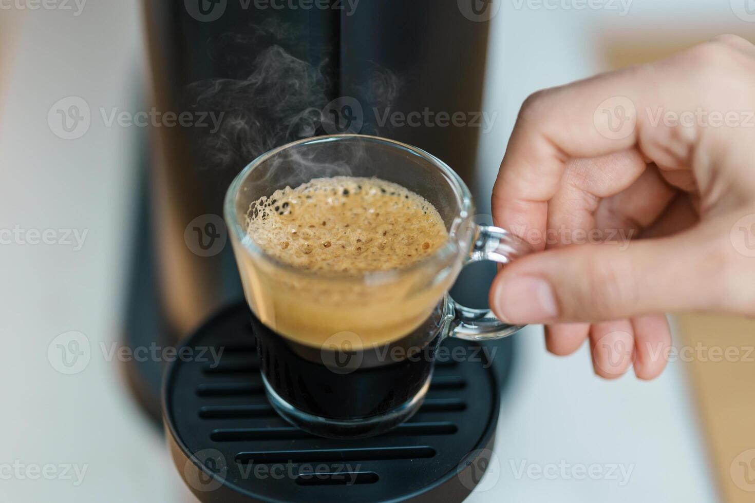 Espresso cup with steam and froth during Coffee making Coffee by Coffee Maker Machine on wood table bar. Cafe shop, Daily beverage drink at Home, Apartment and Office concept photo