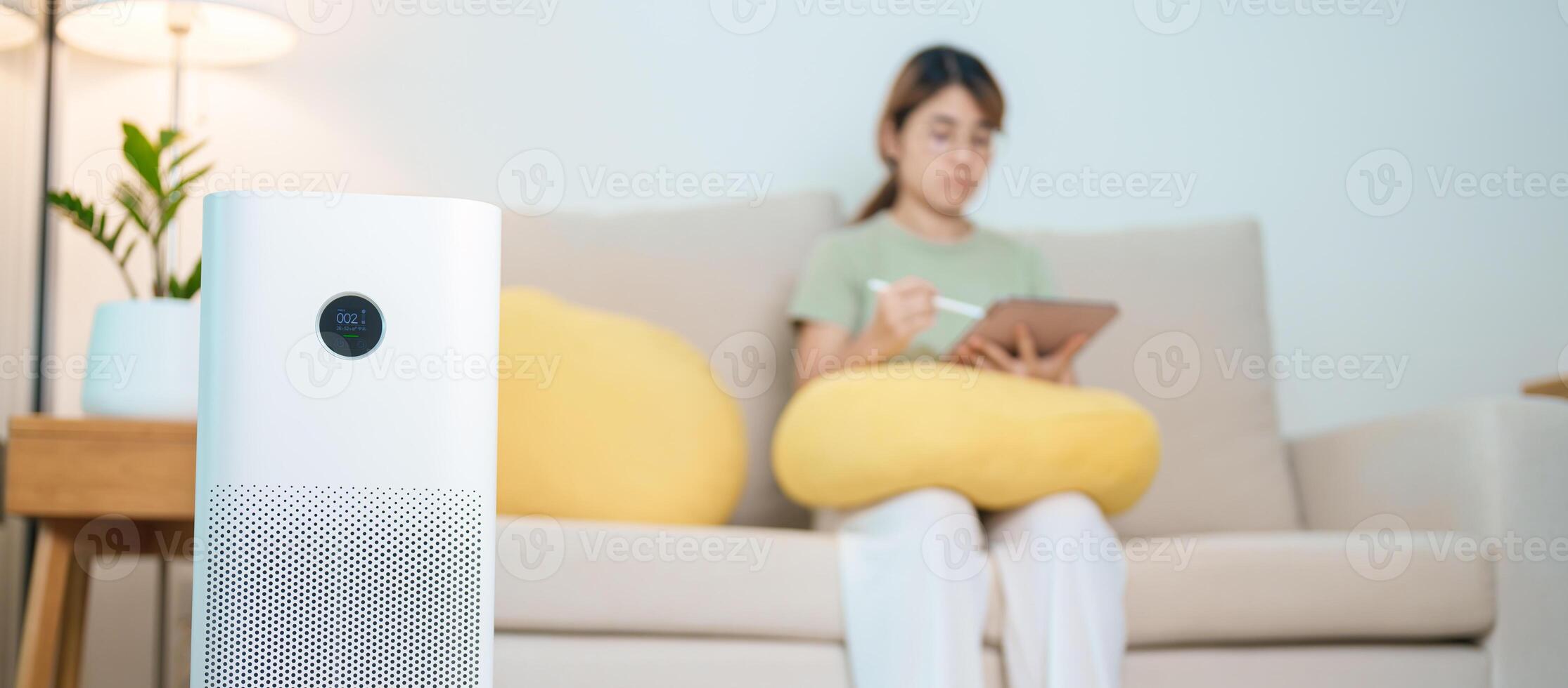 Air Purifier with woman relax and use tablet on sofa. Purification system for filter and cleaning dust PM2.5 HEPA and virus in home. Allergy, Pure air, health, Wellness lifestyle and Air Pollution photo