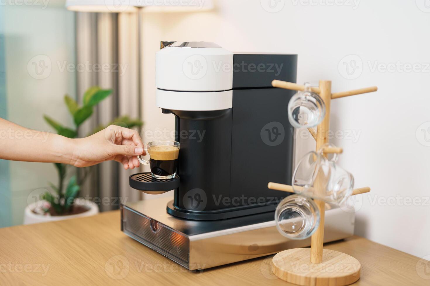 hand making Espresso Coffee by Coffee Maker Machine with Capsule of roasted coffee bean on wood table bar. Daily beverage drink at Home, Apartment and Office concept photo
