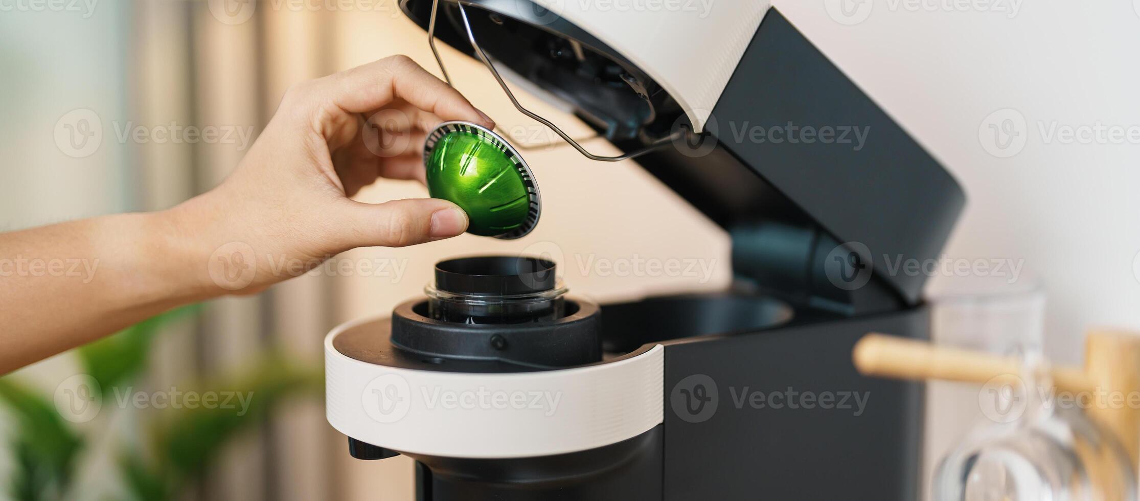 hand making Espresso Coffee by Coffee Maker Machine with Capsule of roasted coffee bean on wood table bar. Daily beverage drink at Home, Apartment and Office concept photo