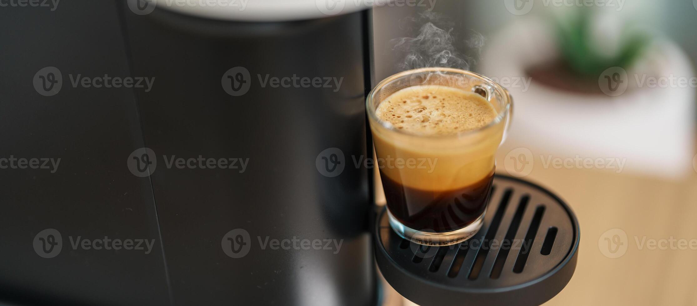 Espresso cup with steam and froth during Coffee making Coffee by Coffee Maker Machine on wood table bar. Cafe shop, Daily beverage drink at Home, Apartment and Office concept photo