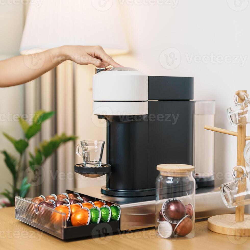 hand making Espresso Coffee by Coffee Maker Machine with Capsule of roasted coffee bean on wood table bar. Daily beverage drink at Home, Apartment and Office concept photo