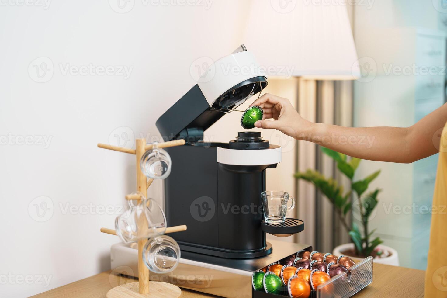 hand making Espresso Coffee by Coffee Maker Machine with Capsule of roasted coffee bean on wood table bar. Daily beverage drink at Home, Apartment and Office concept photo