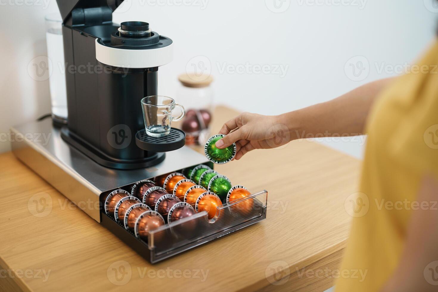 hand making Espresso Coffee by Coffee Maker Machine with Capsule of roasted coffee bean on wood table bar. Daily beverage drink at Home, Apartment and Office concept photo