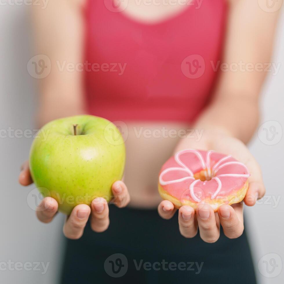 woman hand hold green Apple and donut, female fitness choose between fruit is Healthy and sweet is Unhealthy junk food. Dieting control, Weight loss, Obesity, eating lifestyle and nutrition concept photo
