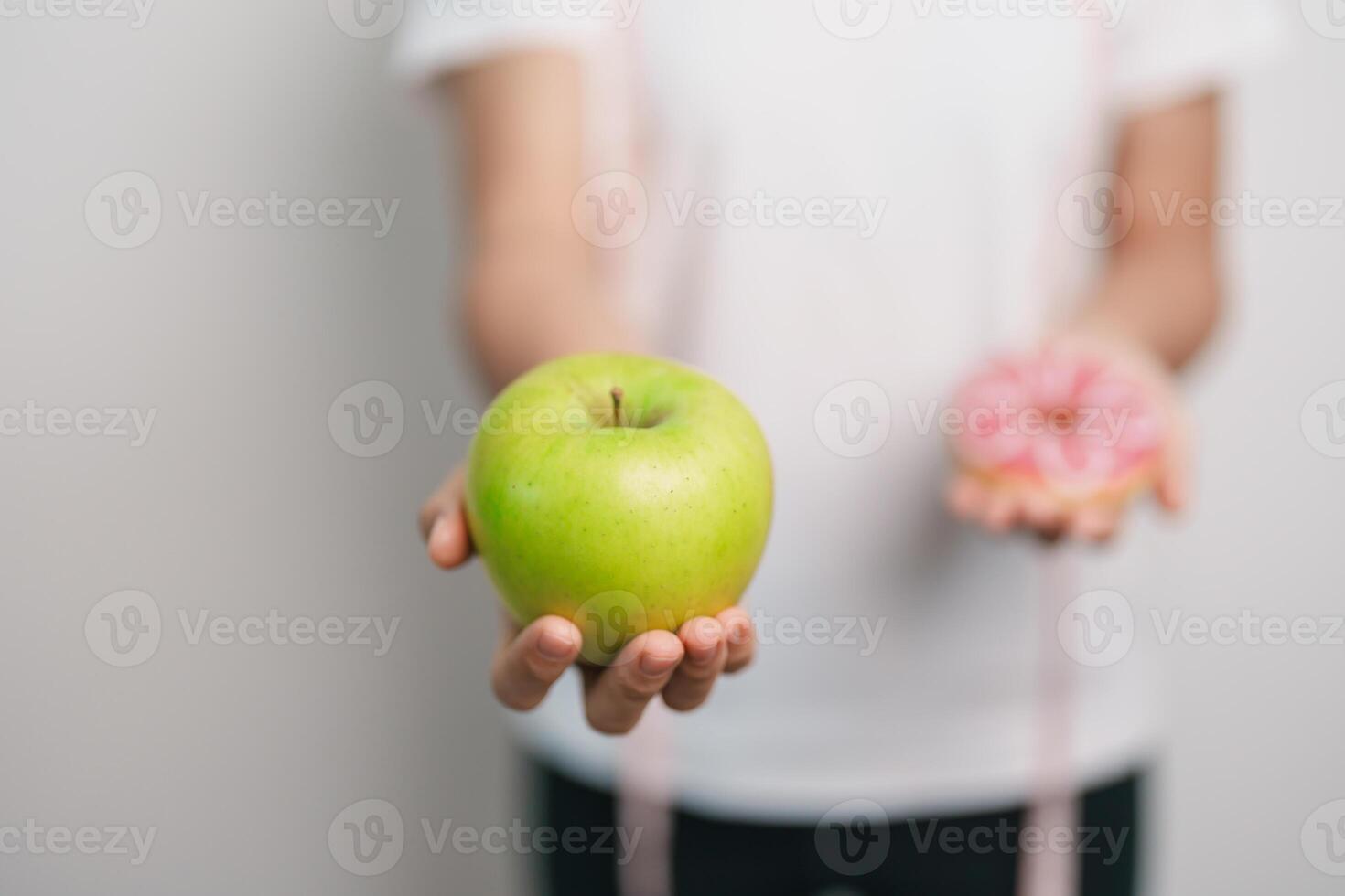 woman hand hold green Apple and donut, female fitness choose between fruit is Healthy and sweet is Unhealthy junk food. Dieting control, Weight loss, Obesity, eating lifestyle and nutrition concept photo