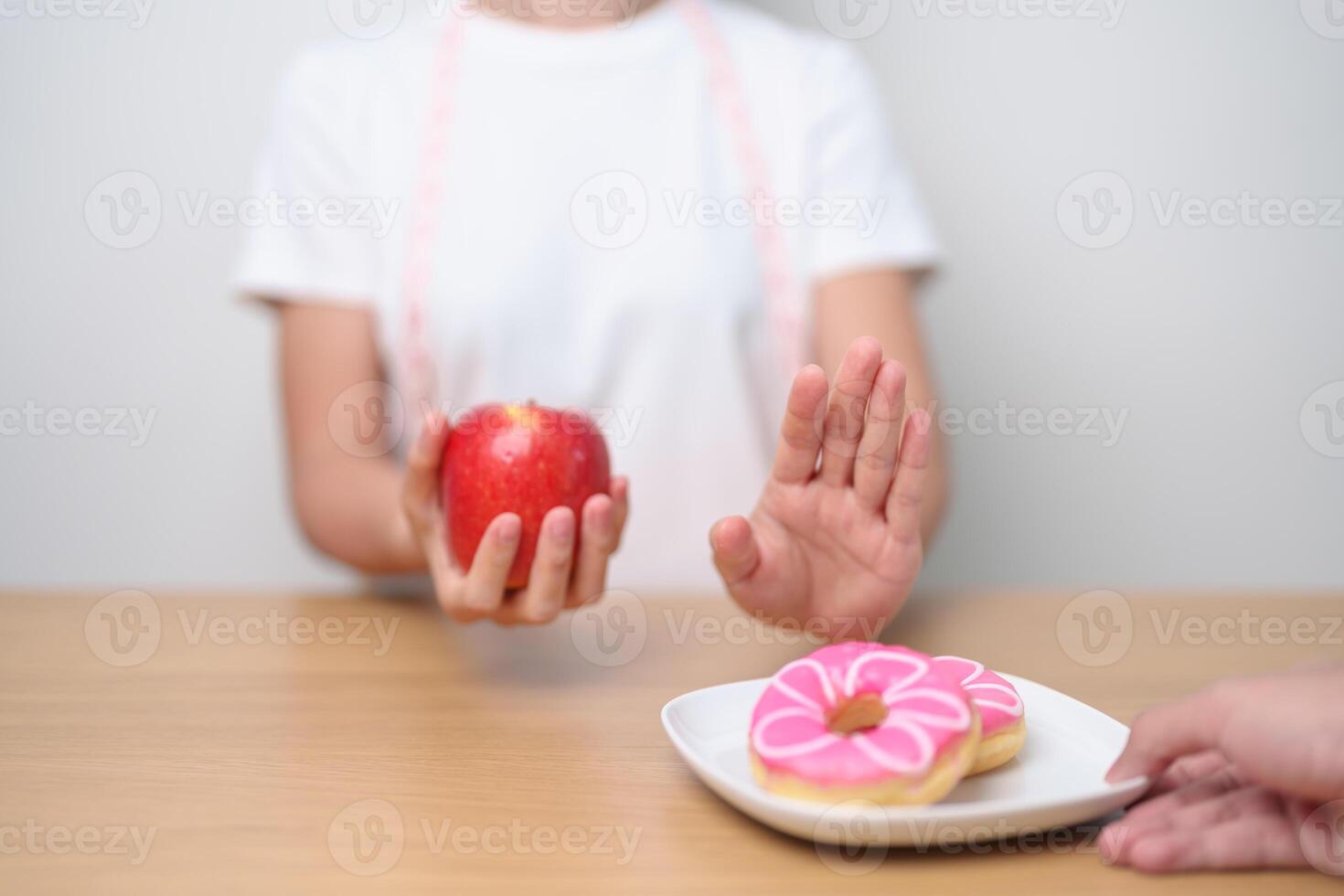 woman hand hold red Apple and reject donut, female fitness choose between fruit is Healthy and sweet is Unhealthy junk food. Dieting control, Weight loss, Obesity, eating lifestyle and nutrition photo