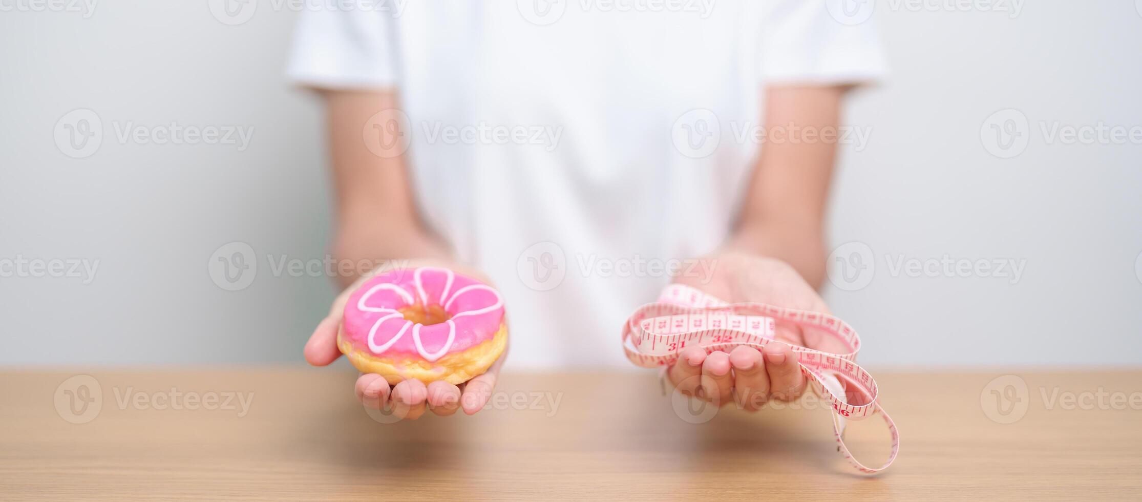 woman hand hold Donut with tape measure, choose stop eating sweet is Unhealthy ealthy food. Dieting control, Weight loss, Obesity, eating lifestyle and nutrition concepts photo