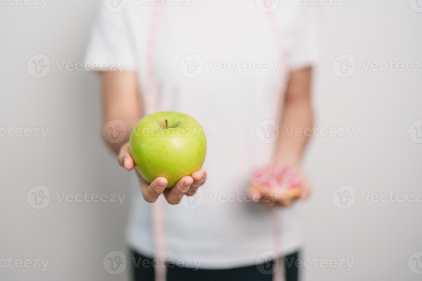 woman hand hold green Apple and donut, female fitness choose between fruit is Healthy and sweet is Unhealthy junk food. Dieting control, Weight loss, Obesity, eating lifestyle and nutrition concept photo